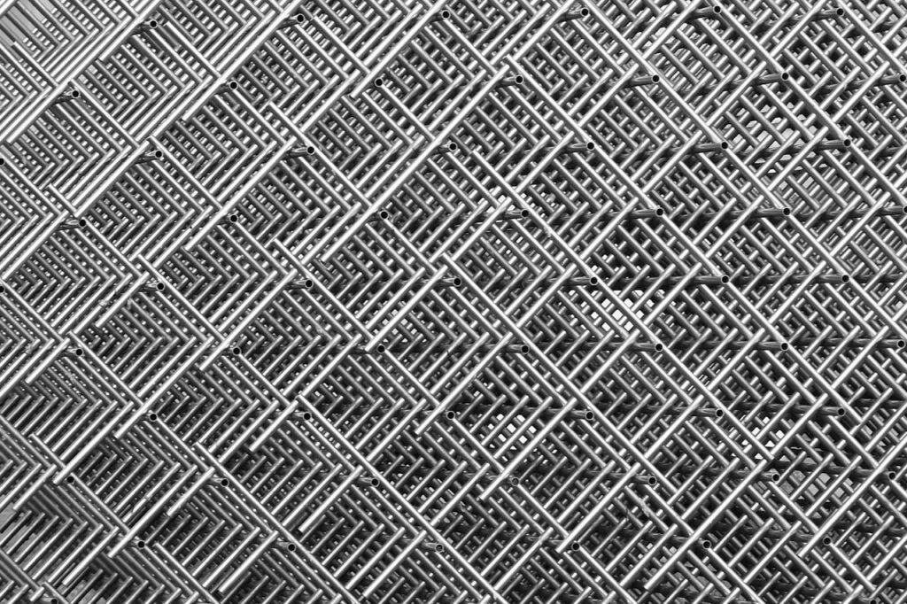 Abstract close-up of interwoven metal grids creating a symmetrical, textured pattern in monochrome.