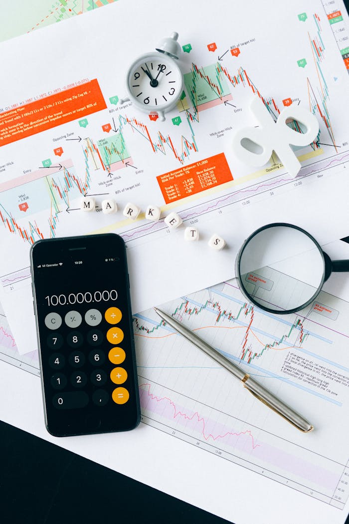 Flat lay of charts, calculator, and magnifying glass on office desk for market analysis.